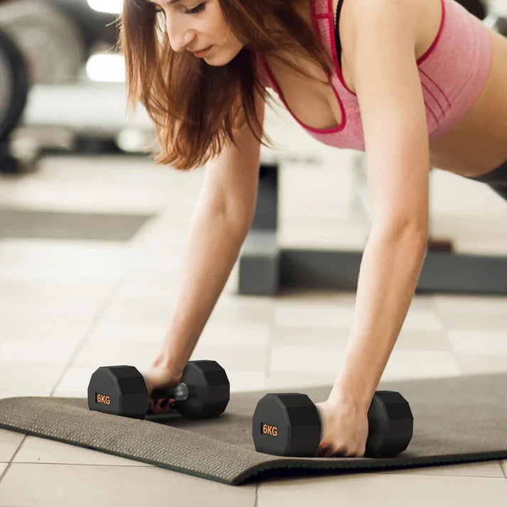 Woman exercising with dumbbells on a mat in an indoor setting